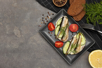 Delicious sandwiches with sprats, cucumber and dill served on grey table, flat lay. Space for text