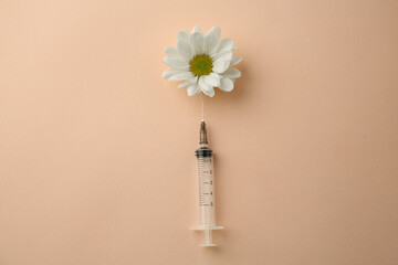 Medical syringe and beautiful chrysanthemum flower on beige background, top view