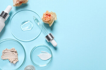 Bottle of cosmetic serum, flowers and petri dishes with samples on light blue background, flat lay....