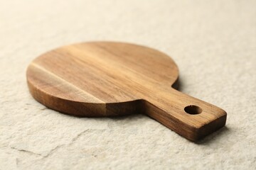 Wooden cutting board on beige table, closeup