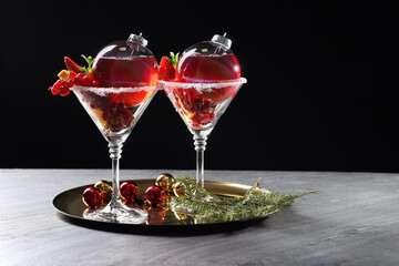 Creative presentation of Christmas Sangria cocktail in baubles and glasses on grey table against black background. Space for text
