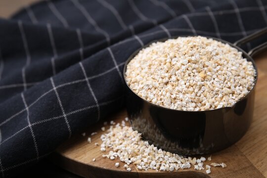 Raw barley groats in scoop on table, closeup. Space for text