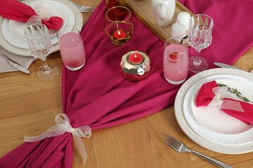 Color accent table setting. Glasses, plates, pink napkins and burning candles, above view