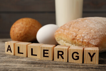 Food allergy. Bread, egg, milk and cubes on wooden table, closeup