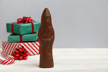 Chocolate Santa Claus candy and Christmas gifts on light wooden table