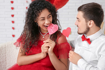 Young couple with heart-shaped lollipop for Valentine's day at home