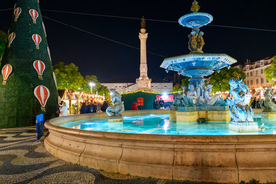 An illuminated Rossio Square Fonte Sul do Rossio fountain with Christmas and holiday decorations at the Rossio Christmas Market in the Baixa district of Lisbon Portugal.