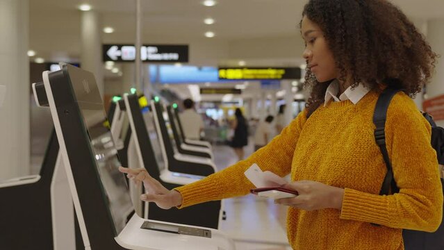 Black women with short, curly hair in airport check-in via automatic machines by herself in the airport to travel or study abroad.