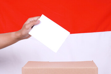 Hand putting ballot in election box with Indonesia flag on the background, close up
