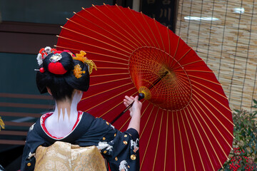 A traditional geisha out and about walking in Gion Kyoto Japan .