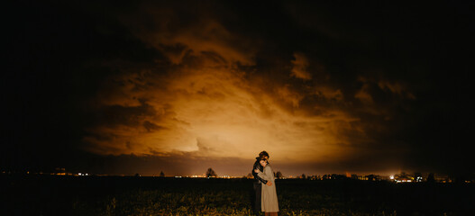 couple in love outside the city at night against the backdrop of an apocalyptic sky with clouds and smoke, a tornado.