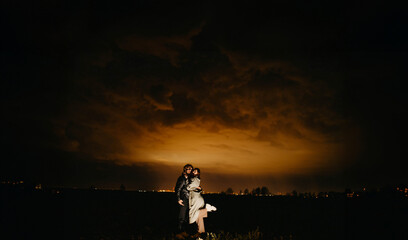 couple in love outside the city at night against the backdrop of an apocalyptic sky with clouds and...