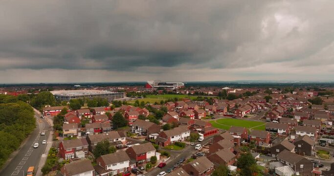 Drone flies above vibrant charming residential neighborhood towards the iconic Anfield football Stadium in Liverpool