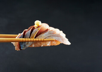 Horse mackerel sushi on chopsticks - obrazy, fototapety, plakaty