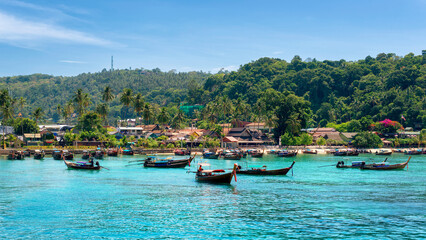 Fototapeta na wymiar Longtail boats in turquoise water in beautiful beach lagoon in tropical island with resorts, Phi-Phi island, Krabi Province, Thailand
