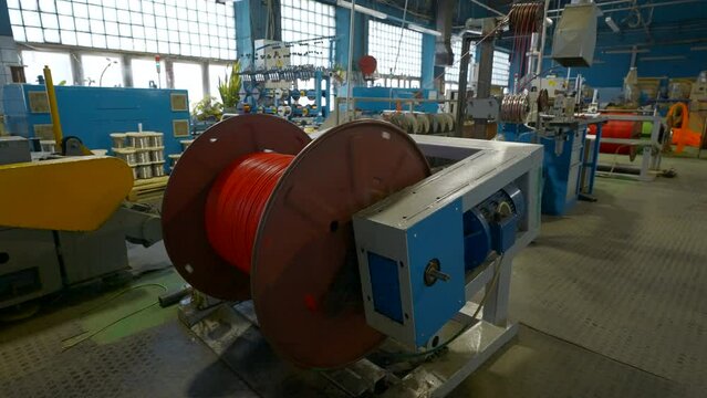 Rotating coil with wires in factory. Creative. Winding cable on to coil on production machine. Process of winding cables at metallurgical plant