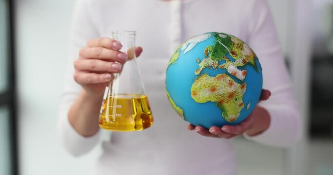 Woman holds flask with oil and globe