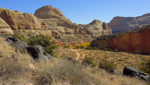Establishing shot of mountain trail with red rocks in Hickman Natural Bridge Trail, Capital Reef National Park, Utah, North America. ProRes 422 HQ.