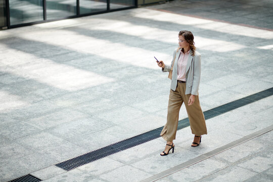 Mature woman checking notifications on smartphone when walking in the street