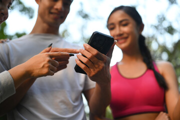 Healthy Asian man and woman friends using mobile phone after morning workout.