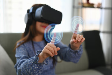 Little girl wearing VR headset and touching virtual button interacting with digital interface