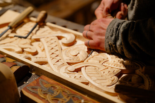 In this captivating scene, a masterful carpenter demonstrates meticulous attention to detail while crafting intricate designs on wood, showcasing exceptional woodworking artistry and skill.