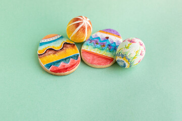 galleta con forma de huevo de pascua pintado a mano junto con dos huevos cocidos decorados