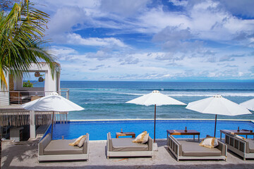 Beach bar and restaurant. Infinity pool and sun beds with white parasol umbrella