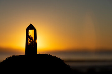 A beautiful peaceful image of a smoky quartz crystal tower against the backdrop of a bright golden...