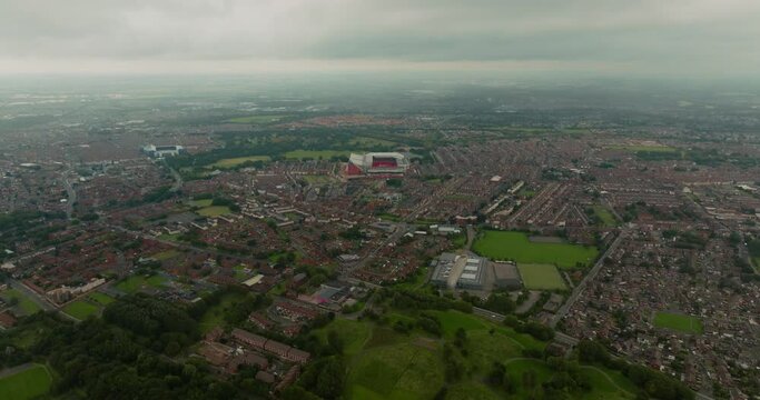 Drone flies above urban landscape of Liverpool towards iconic football ground Anfield on moody day