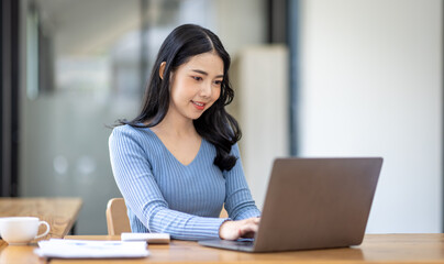 Asian Business woman using calculator and laptop for doing math finance on an office desk, tax, report, accounting, statistics, and analytical research concept
