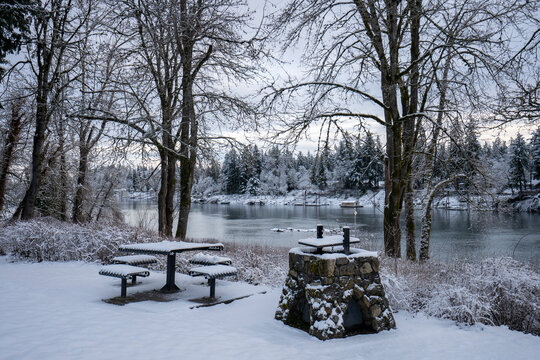 Snow-covered outdoor picnic table and fire pit in a park in Lake Oswego, Oregon, overlooking the Willamette River, on a cold winter morning after overnight snowfall. - Powered by Adobe
