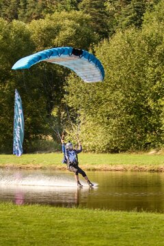 Isolated skydiver with bright colorful parachute on jumping, landing to the water during sunny day, Klatovy, Czechia