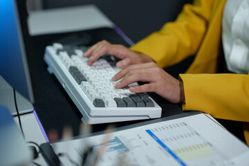 Successful Asian businesswoman sitting at desk typing numeric data on PC keyboard in modern office Business technology career concept.