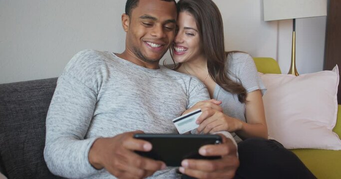 Millennial couple booking expensive hotel online together on smartphone. Couple using cell phone to make large purchase with their credit card. 4k slow motion handheld
