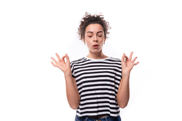 young curly brunette woman in a striped t-shirt is meditating