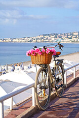 France. Nice. Bicycle with a beautiful basket filled with pink flowers in front of the sea