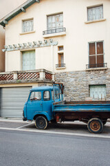 Un vieux camion benne bleu devant une vieille maison. Un vieux véhicule abandonné devant une maison abandonnée.