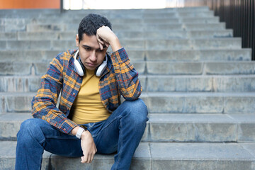 Worried and sad latin ypoung man sitting on uran stairs © Egoitz