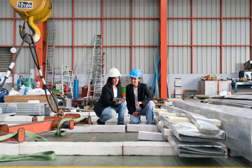 Two women wearing safety hats are energetically working together in a spacious and organized...