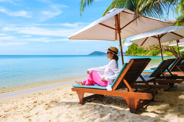 Asian woman on a beach chair on the beach of Koh Samet Island Rayong Thailand, the white tropical beach of Samed Island with a turqouse colored ocean on a sunny day - obrazy, fototapety, plakaty