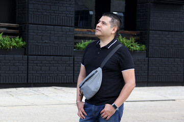 40-year-old dark-skinned Latino man uses crossbody bag also called fanny pack, chest bag that...