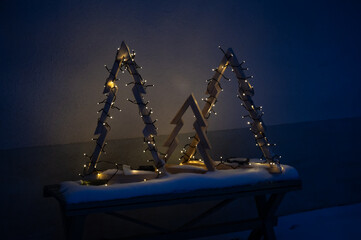 Three home made wooden Christmas trees with lights outside