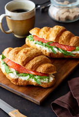 Croissants with salmon, white cheese and arugula. Breakfast.