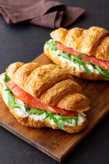 Croissants with salmon, white cheese and arugula. Breakfast.