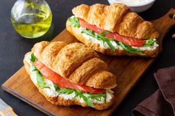 Croissants with salmon, white cheese and arugula. Breakfast.