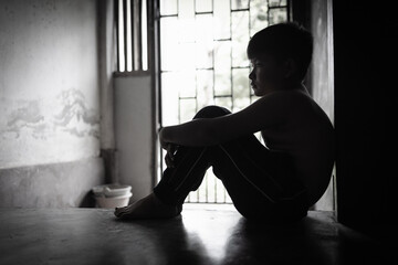 Child abuse concept, silhouette of  child confined in a dark room, prisoner or child abduction,...