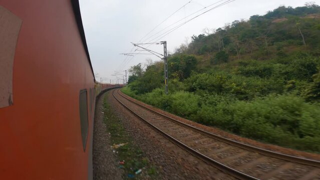 3rd December, 2023, Singapore Road, Orisa, India: A yellow long Indian railway diesel locomotive passenger train in countryside of dooars area on curvy stretch of track with selective focus.