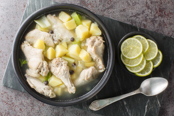 Chicken souse is a broth consisting of chicken, vinegar, potatoes, vegetables closeup on the plate on the table. Horizontal top view from above