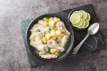 Chicken souse is a Bahamian soup consisting of clear broth where the meat and the vegetables are boiled down in the juice of fresh citrus closeup on the plate on the table. Horizontal top view